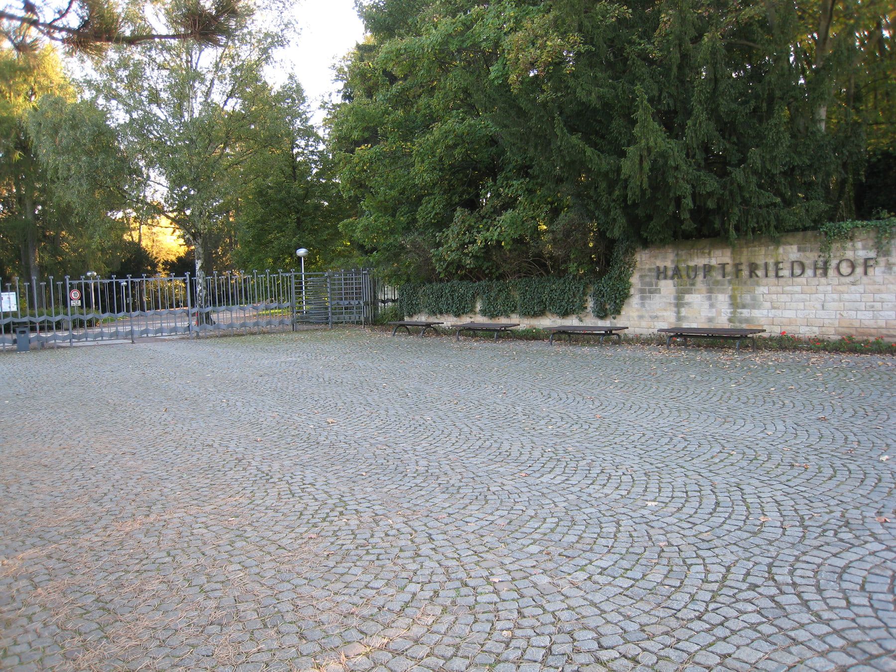 Haupteingang mit Namensmauer, Metalltor und weitem Pflastervorplatz auf Hauptfriedhof Erfurt